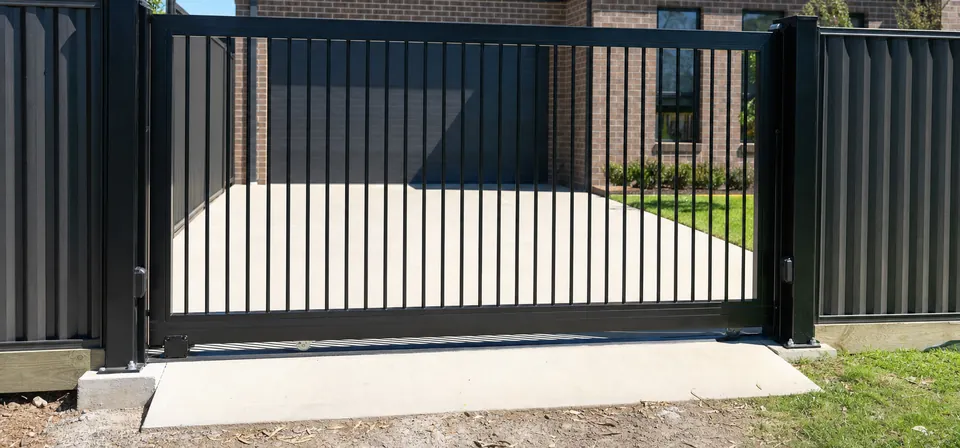 Black steel sliding driveway gate on a concrete base
